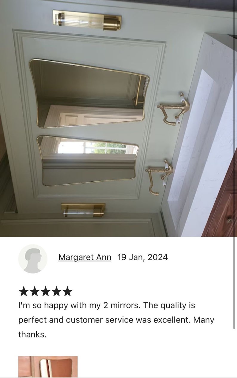 May include: Two gold-framed, beveled-edge mirrors with a decorative design, mounted on a light green wall. The mirrors are angled and reflect the surrounding space.