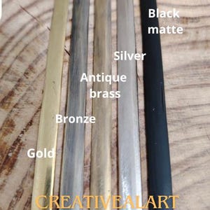 Op de afbeelding: Vijf verschillende gekleurde metalen stroken, met de labels "Gold", "Bronze", "Antiek messing", "Zilver" en "Zwart mat". De stroken zijn verticaal gerangschikt, met de gouden strook links en de zwart matte strook rechts. De tekst "CREATIVEALART COLORS" is onder de stroken gedrukt.