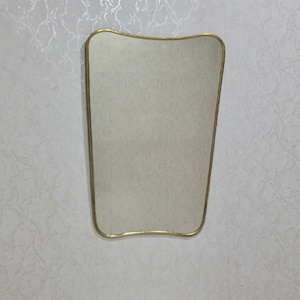 May include: A gold-framed, wavy-edged mirror with a reflective surface.