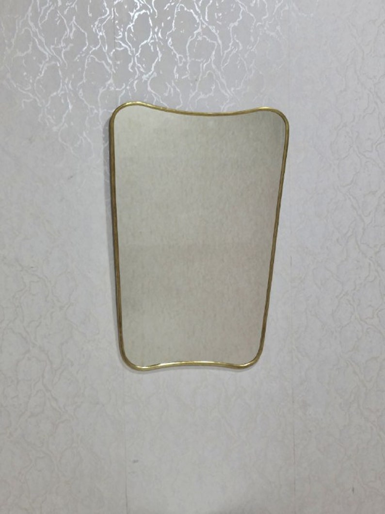 May include: A gold-framed, wavy-edged mirror with a reflective surface.