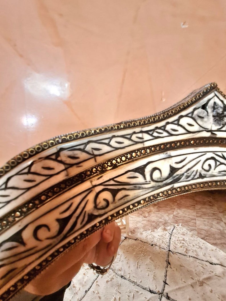 Op de afbeelding: Een decoratief, versierd, wit en zwart, gesneden houten frame met een gouden rand. Het frame is gebogen en heeft een bloemmotief.