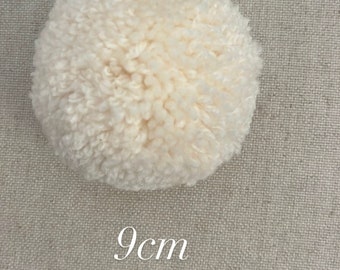 May include: A white fluffy pom pom measuring 9 cm in diameter.