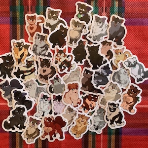 Könnte beinhalten: Eine Sammlung von 40 bunten Comic-Katzenaufklebern. Die Aufkleber zeigen verschiedene Katzenrassen und Posen, darunter eine schwarze Katze, eine getigerte Katze, eine dreifarbige Katze und eine weiße Katze. Die Aufkleber sind perfekt, um Laptops, Wasserflaschen, Tagebüchern und vielem mehr einen Hauch von Verspieltheit zu verleihen.