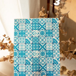 May include: A white card with a blue and white patterned design. The pattern is made up of small squares with different geometric shapes and floral motifs.