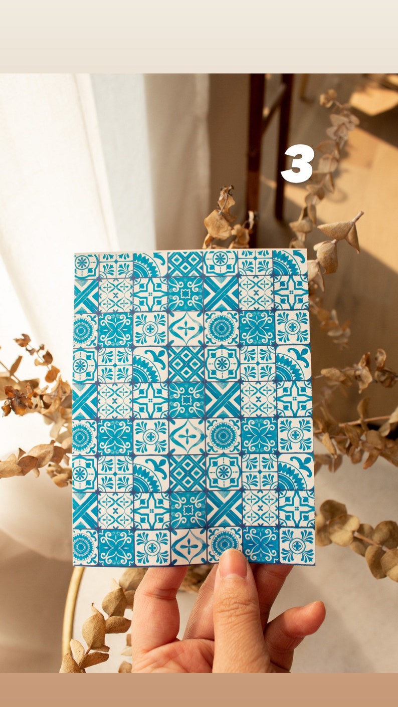 May include: A white card with a blue and white patterned design. The pattern is made up of small squares with different geometric shapes and floral motifs.