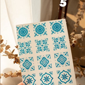 May include: A sheet of 9 blue and white patterned tile stickers. The stickers are arranged in 3 rows of 3. The stickers are on a white background.