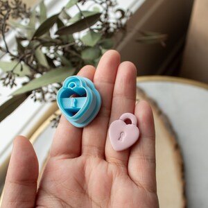 May include: Two heart-shaped cookie cutters, one light blue and one pink, with a keyhole design.