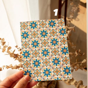 May include: A close-up of a card with a repeating pattern of blue, orange, and yellow flowers on a white background.