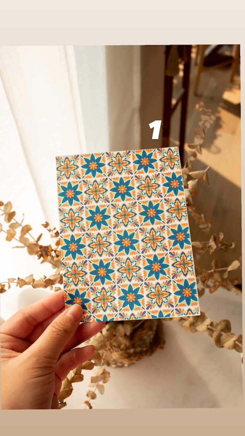 May include: A close-up of a card with a repeating pattern of blue, orange, and yellow flowers on a white background.