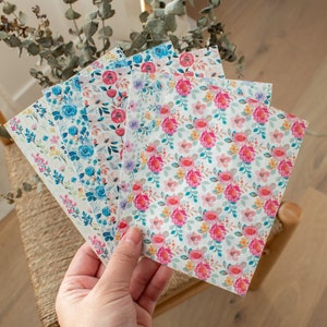 May include: A set of five floral patterned paper sheets. The sheets feature different floral designs with pink, blue, and yellow flowers on a white background.