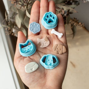 Peut inclure: Ensemble de découpoirs à biscuits et friandises sur le thème des animaux de compagnie. Les découpoirs sont bleu clair et en forme d'empreinte de patte, de chat, de chien et de gamelle. Les friandises ont la forme d'une empreinte de patte, d'un chat, d'un chien, d'un os et d'une gamelle.