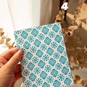 May include: A white card with a blue and white geometric pattern. The card is being held by a hand.