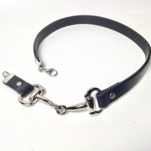 May include: A black leather choker necklace with a silver horse bit clasp.