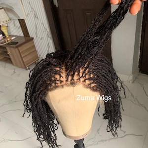 May include: A black dreadlock wig on a mannequin head. The wig is styled with individual locs and a natural-looking hairline. The text "Zuma Wigs" is visible on the mannequin head.