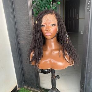 May include: A dark brown lace front wig featuring thin, textured locs that fall to the shoulders. The wig is displayed on a mannequin head and includes small, colorful decorative beads woven into several of the individual loc strands.