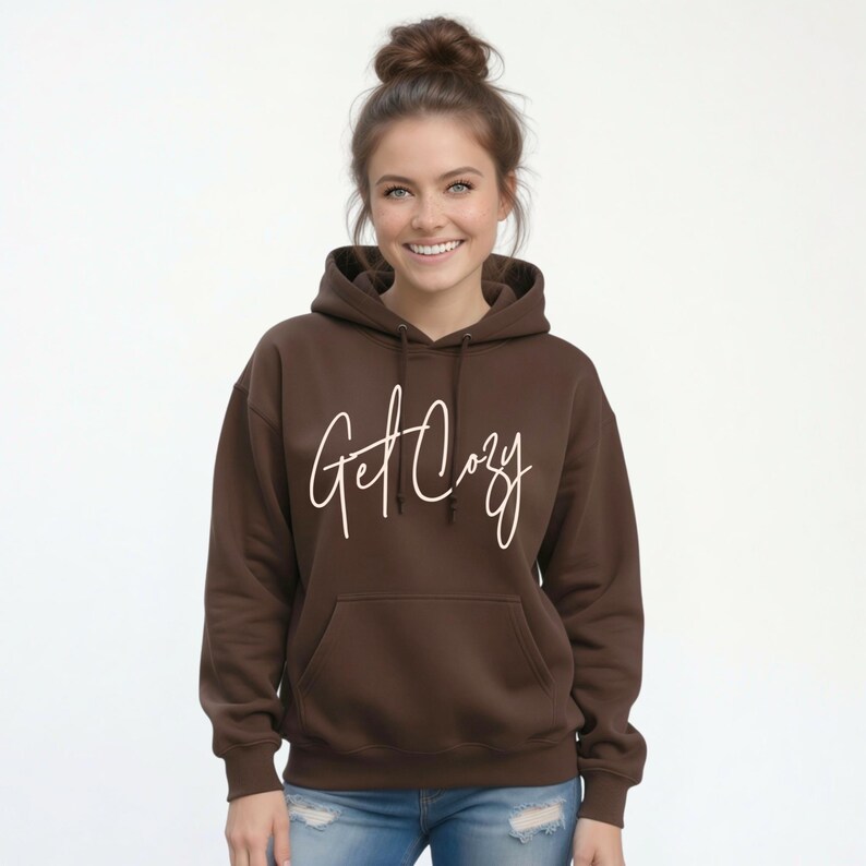 Woman wearing a brown Get Cozy hoodie with white script and jeans for a cozy fall outfit.