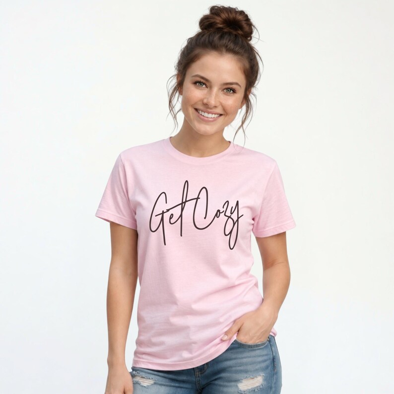 Woman wearing a light pink Get Cozy T-shirt with black script and distressed jeans for a casual fall outfit.