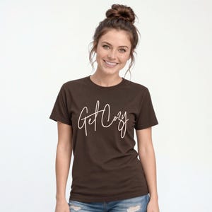 Woman wearing a brown Get Cozy T-shirt with white script and jeans for a casual fall outfit.