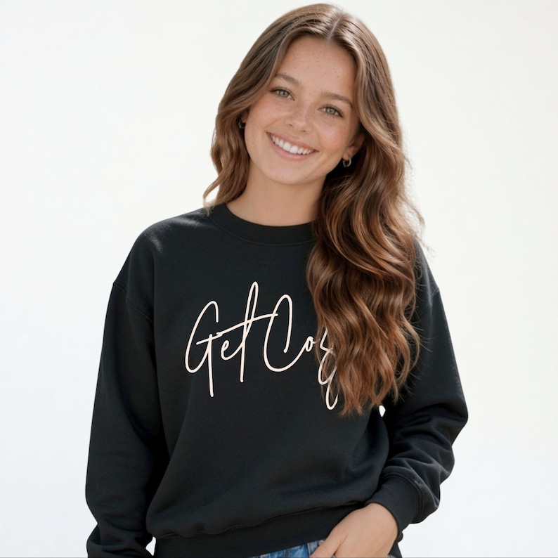 Girl wearing a black Get Cozy youth sweatshirt with white script and jeans.
