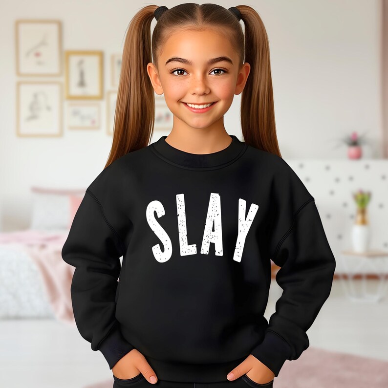 Black youth sweatshirt with bold white SLAY design, kids trendy graphic crewneck for girls and teens, cute aesthetic fashion outfit mockup, unisex fleece pullover.