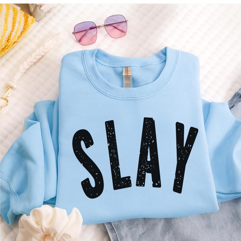 Sky blue SLAY sweatshirt with bold black distressed text, perfect for confident teens and girls. Youth and adult sizes, cozy cotton blend, Gen Z aesthetic, ideal for back to school, TikTok, birthdays, and fall weather layering.