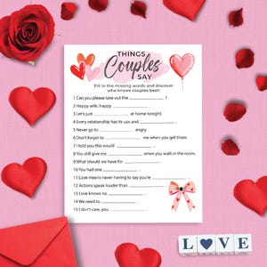 以下が含まれることがあります： 「Things Couples Say」というテキストと穴埋め問題があるバレンタインデーのゲーム。画像には赤いハート、バラの花びら、赤いバラ、赤い封筒が含まれています。「LOVE」という単語は文字ブロックで綴られています。
