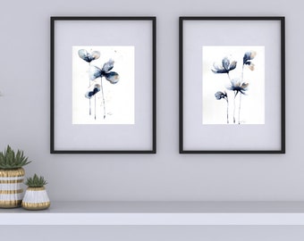 Könnte beinhalten: Zwei gerahmte Aquarellbilder von blauen Blumen mit goldenen Akzenten. Die Bilder sind in schwarzen Rahmen und hängen an einer weißen Wand.