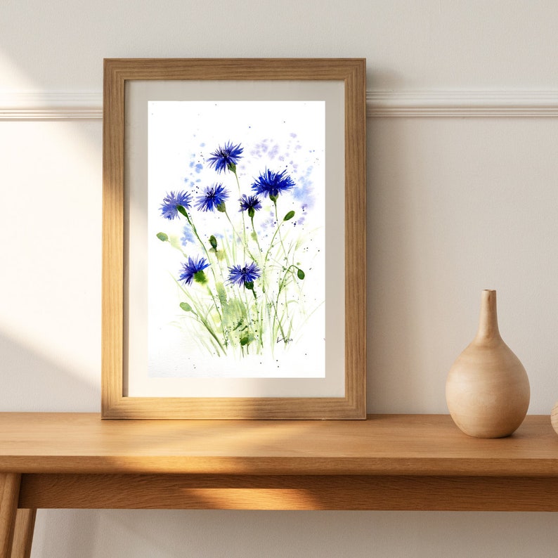 May include: A framed watercolor painting of blue wildflowers with green stems and leaves on a white background.