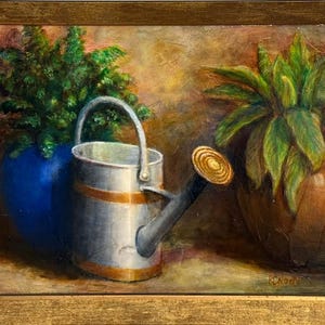 May include: An oil painting of a still life featuring a silver watering can with gold accents, positioned in front of a blue vase with green foliage. A brown pot with green leaves is on the right. The painting is in a gold frame.