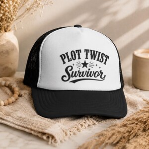 Puede incluir: Gorra de camionero en blanco y negro con el texto "PLOT TWIST Survivor" en negro y una estrella. La gorra tiene una visera negra, una parte trasera de malla y un panel frontal blanco.