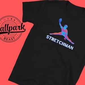 May include: Black t-shirt featuring a colourful graphic of a baseball player in a stretching pose. The text "STRETCHMAN" is printed below the graphic. The text "Ballpark Beast" is printed on a circular logo in the top left corner.