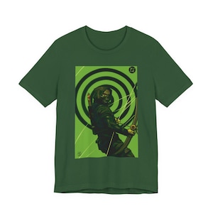May include: A dark green short-sleeve t-shirt featuring a graphic print of a hooded archer in black and green tones. The archer holds a bow and arrow against a background of black concentric circles on a light green field with diagonal lines.