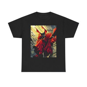 Peut inclure: Un t-shirt noir à manches courtes avec une impression graphique centrée représentant un personnage masqué en costume sombre avec une cape rouge vif flottante. Le fond de l'image montre un ciel jaune avec des silhouettes de chauves-souris.