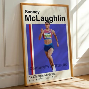 May include: Framed poster featuring Sydney McLaughlin, a 4x Olympic medallist, in a running pose. The poster has a blue background with red and white vertical stripes. Text includes her name and "CenturyPrintStudio".