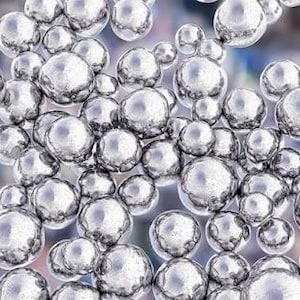 Op de afbeelding: Een verzameling van talloze metallic zilveren bollen van verschillende groottes, gerangschikt in een dichte cluster. Het oppervlak van elke bol is sterk reflecterend, met heldere accenten en donkere schaduwen voor een 3D-effect.