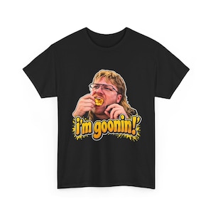 Könnte beinhalten: Ein schwarzes T-Shirt mit kurzen Ärmeln und einem Grafikdruck einer Person mit Vokuhila und Brille, die einen gelben Snack isst. Unter dem Bild ist der Text "i'm goonin!" in fetten, gelben Buchstaben im Used-Look aufgedruckt.