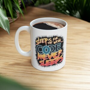 May include: White ceramic mug with a black and yellow graphic that says "Sleep is for the weak. Code never sleeps."
