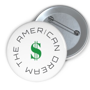 May include: A white button with a green dollar sign in the centre and the text "The American Dream" written in a circle around the dollar sign.