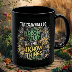 May include: Black ceramic coffee mug with a white design that says "That's what I do I grow stuff and I know things". The design features a green watering can and flowers.