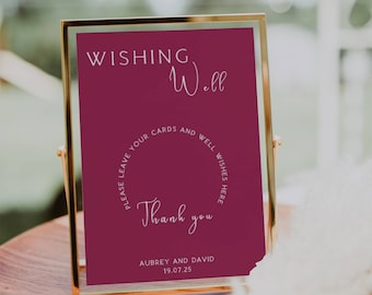 May include: A burgundy sign in a gold frame with the text "WISHING Well PLEASE LEAVE YOUR CARDS AND WELL WISHES HERE Thank you AUBREY AND DAVID 19.07.25"