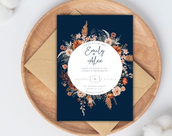May include: A navy blue wedding invitation with a white circle in the center. The circle contains the names "Emily + Alex" and the wedding date "October 26, 20XX". The invitation is decorated with a wreath of watercolor flowers in shades of orange, red, and white.