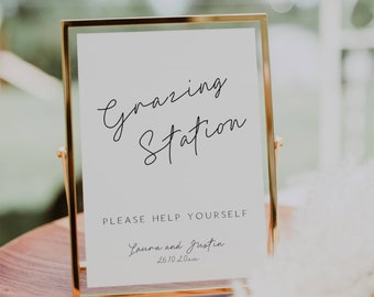 May include: A gold-framed sign with the text "Grazing Station" in cursive script. Below the text, it reads "Please help yourself" and "Laura and Justin 26.10.20xx".