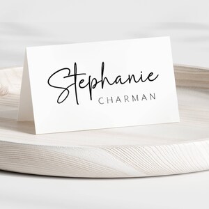 May include: White place card with black calligraphy text that reads "Stephanie Charman".