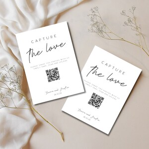 Puede incluir: Dos tarjetas blancas con texto negro que dice "Capture the love". Cada tarjeta tiene un código QR y el texto "Por favor, comparte tus fotos con nosotros, simplemente toma una foto, escanea y sube". Las tarjetas también tienen los nombres "Laura y Justin" y la fecha "26.10.24".