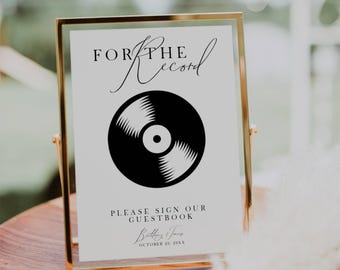 May include: A gold-framed sign with a black vinyl record graphic and the text "For the Record" in a cursive font. The sign also includes the text "Please sign our guestbook" and the names "Brittany & James" with the date "October 20, 20XX".