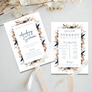 May include: Wedding ceremony program fans with a floral design in shades of blue, orange, and beige. The fans feature the names "Audrey & Simon" and the order of events for the wedding ceremony.