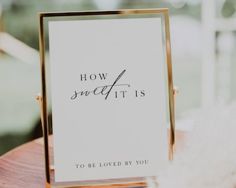 May include: A gold-framed sign with the text "How sweet it is to be loved by you" in black calligraphy.