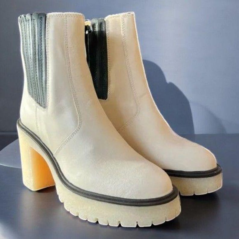 May include: A pair of off-white ankle boots with black elastic panels on the sides and a thick platform sole.
