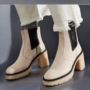 May include: A pair of cream-coloured ankle boots with black elastic panels and chunky heels. The boots have a platform sole and are made of leather.