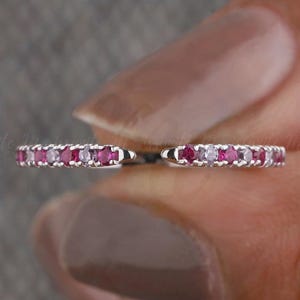 Op de afbeelding: Een delicate zilveren bandring met een rij kleine roze en witte edelstenen.